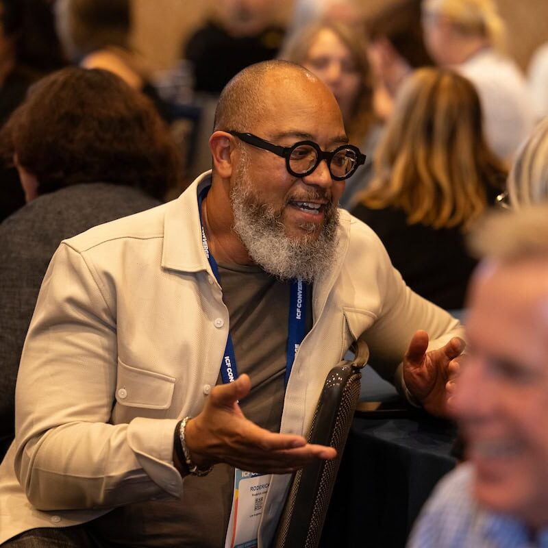 Conference attendee in conversation with peers during ICF Converge Day Two event session.