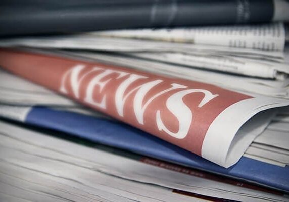 news papers stacked with one pulled out showing the word news