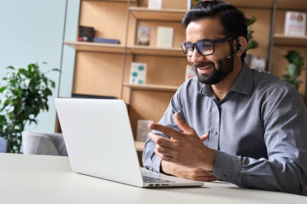 coach smiling with a headset on and speaking to a computer screen on a video call