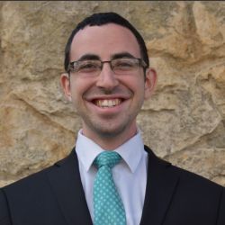 Joseph Bernstein headshot photo, dark haired man with glasses suit and green tie smiling