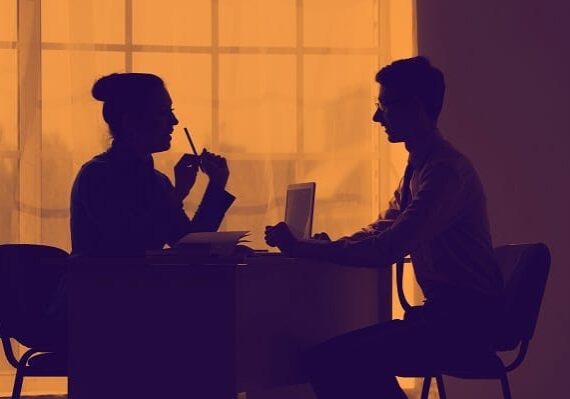 woman delivering feedback to a man across a desk