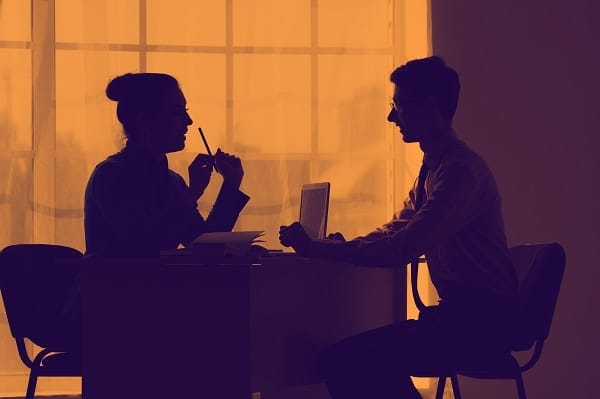 woman delivering feedback to a man across a desk