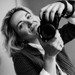 Dasha Dare ACC headshot photo, woman holding a camera smiling taking a photo