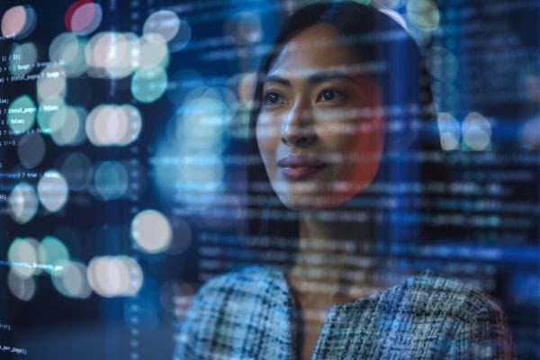 woman looking at transparent screen with code and light spots