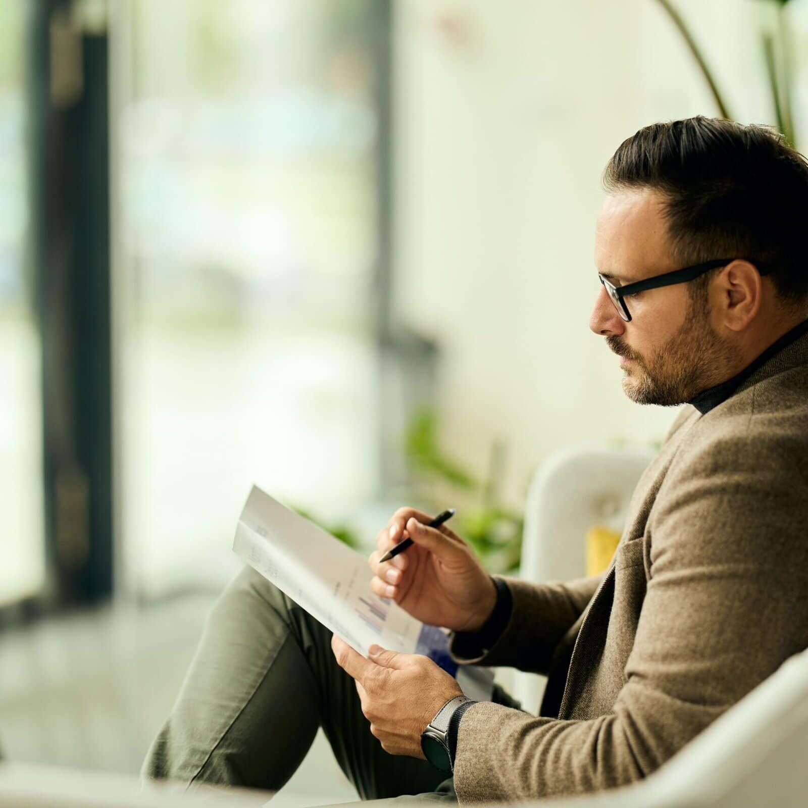 Professional sitting in an office chair taking notes on paper