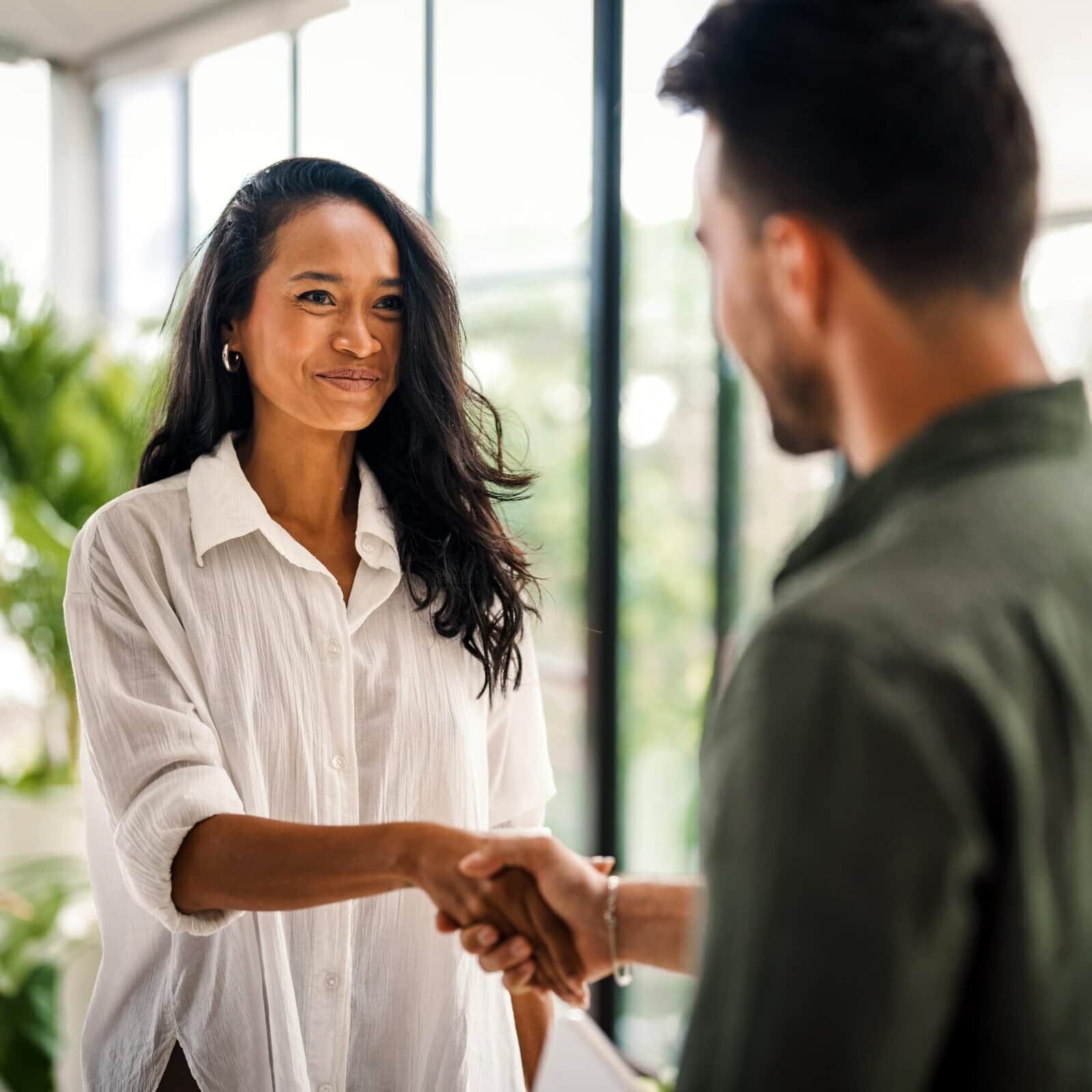 Two professionals shaking hands during a meeting in a modern office