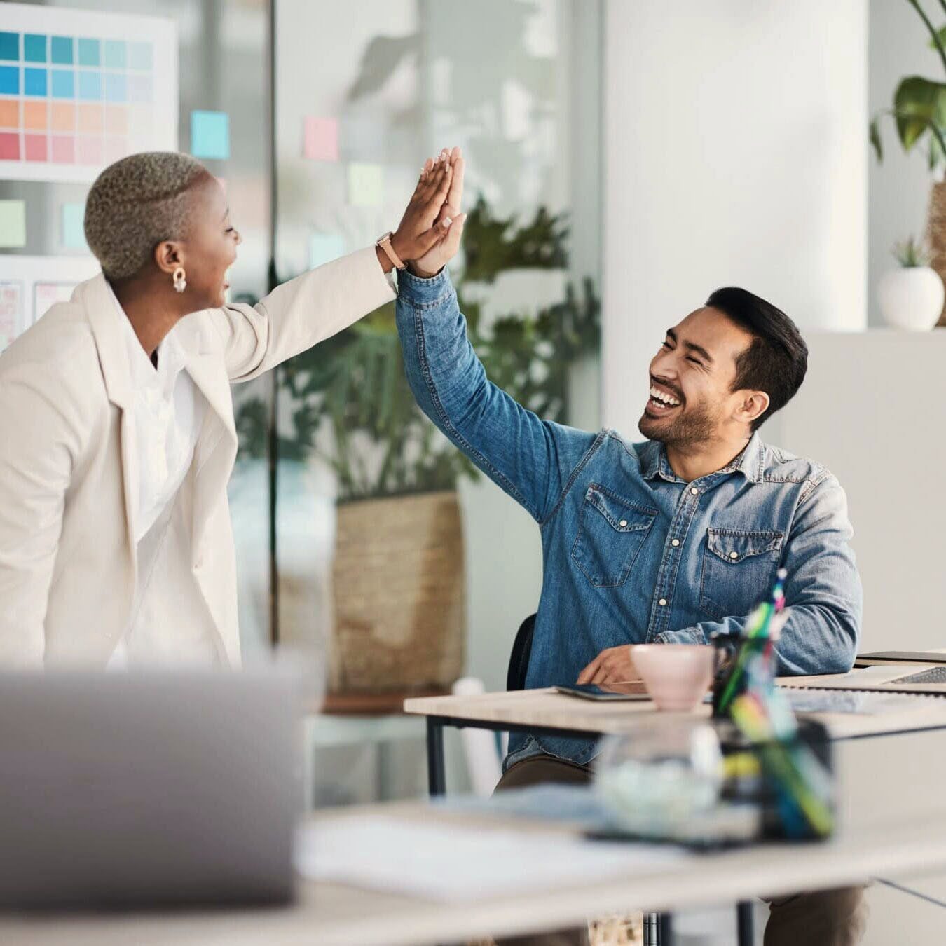 A man and a woman high five in an office setting.