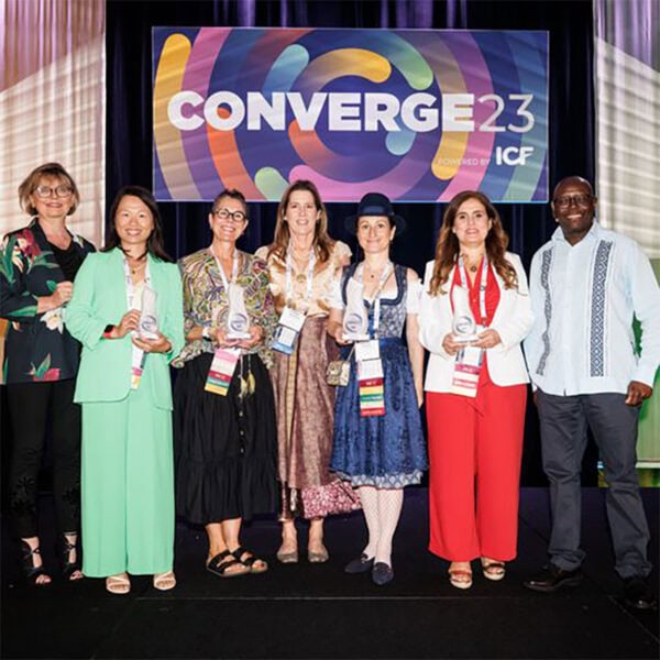 A group photo of the 2023 ICF Coaching Impact Award winners in the "Coaches" category at ICF Converge 2023, holding their awards in recognition of their outstanding contributions to the coaching profession.