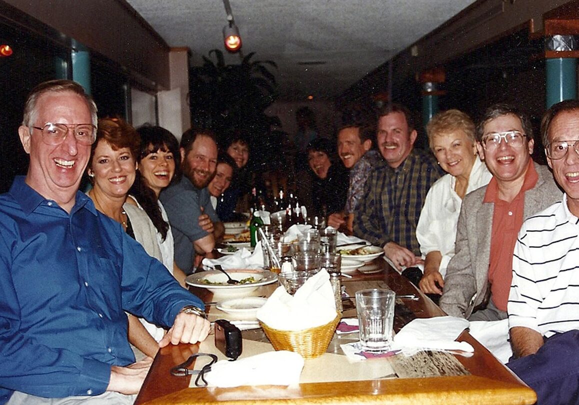 A historical photo of one of the first boards of directors for the International Coaching Federation, seated around a dining table during a meal.