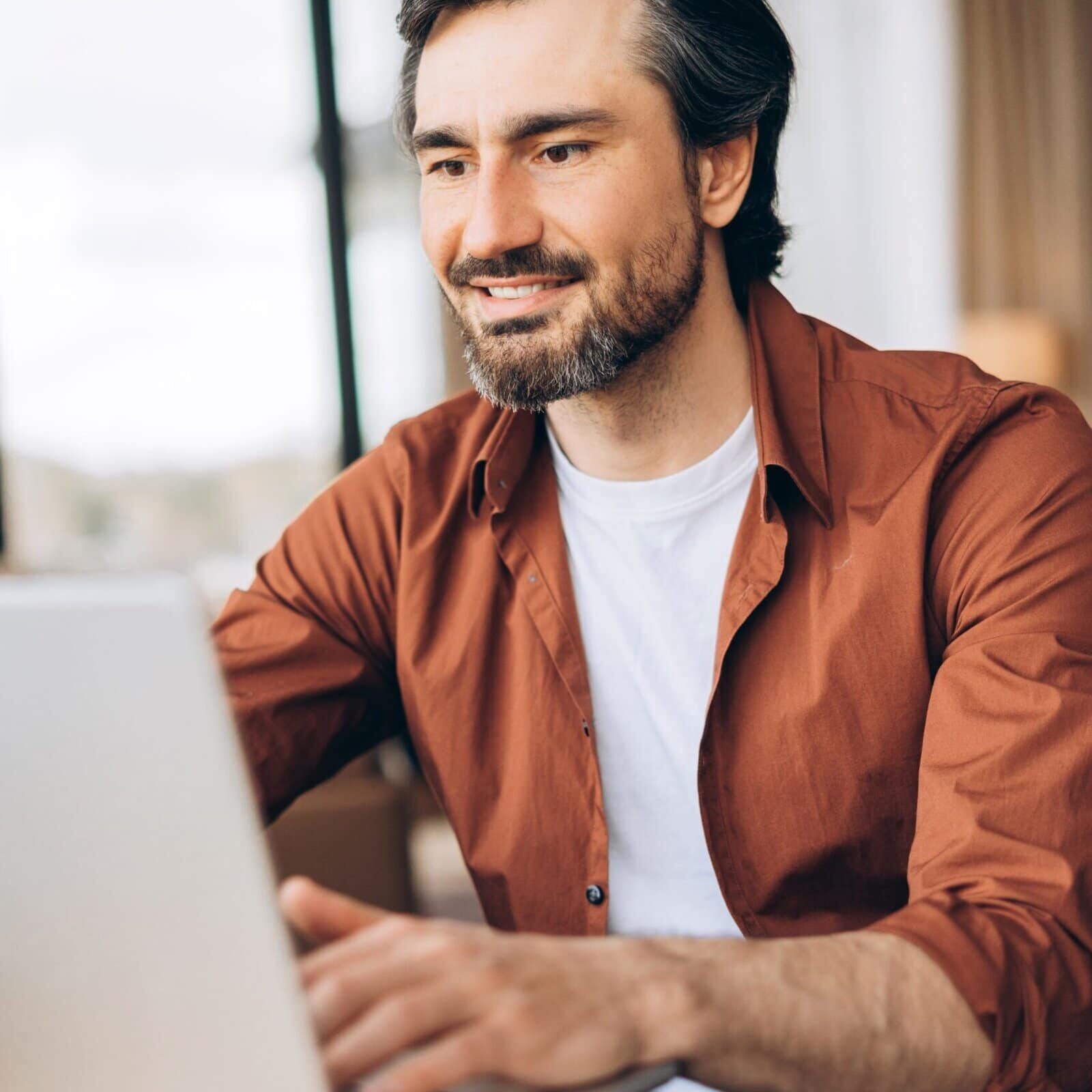 Happy,Male,Freelancer,With,Beard,And,Brown,Shirt,Is,Working