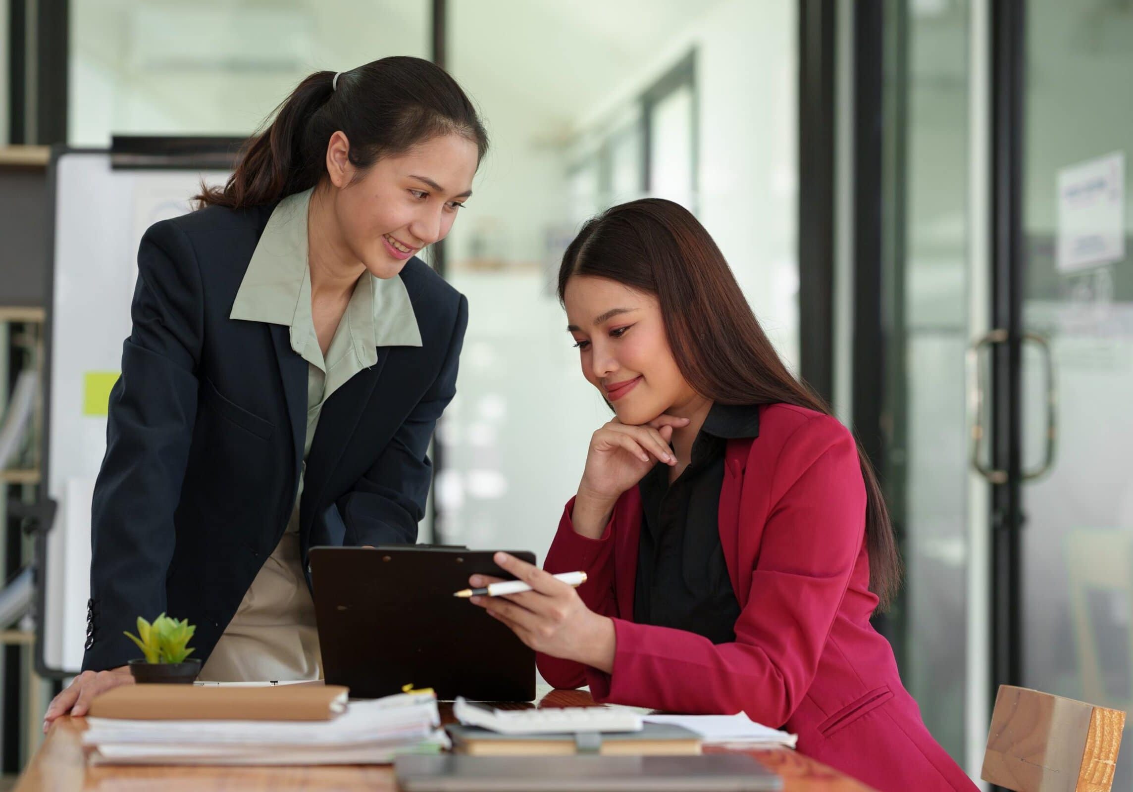 Two professionals reviewing information together at a desk in an office