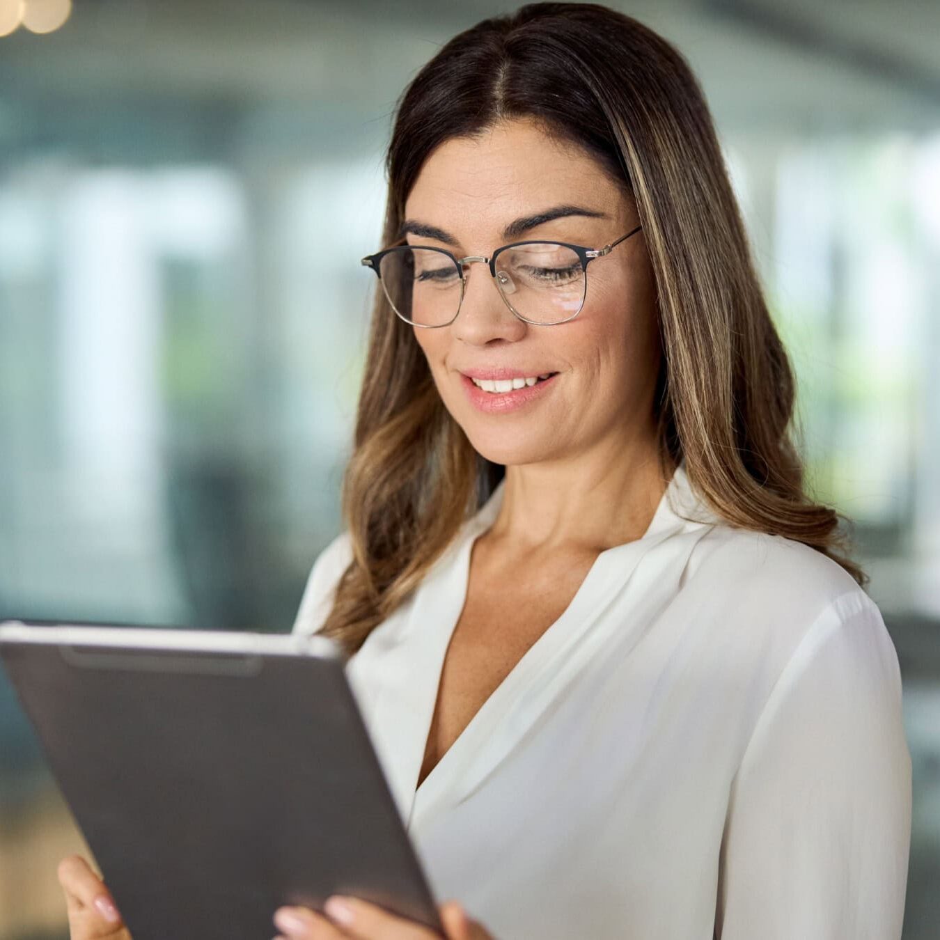 A woman views her tablet in an office setting to find out more information about ICF Strategic Alliances.