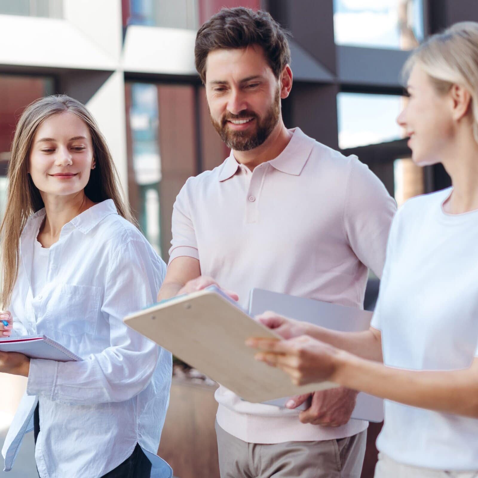 Three young coworkers walking together while reviewing documents