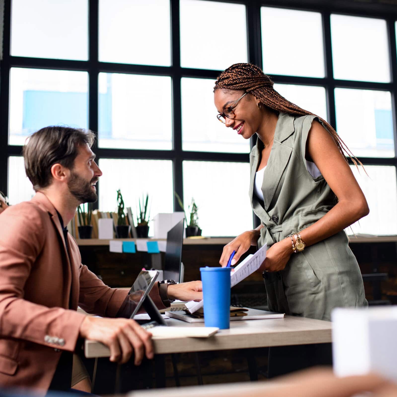 Two professionals discussing documents at a desk in a modern office setting