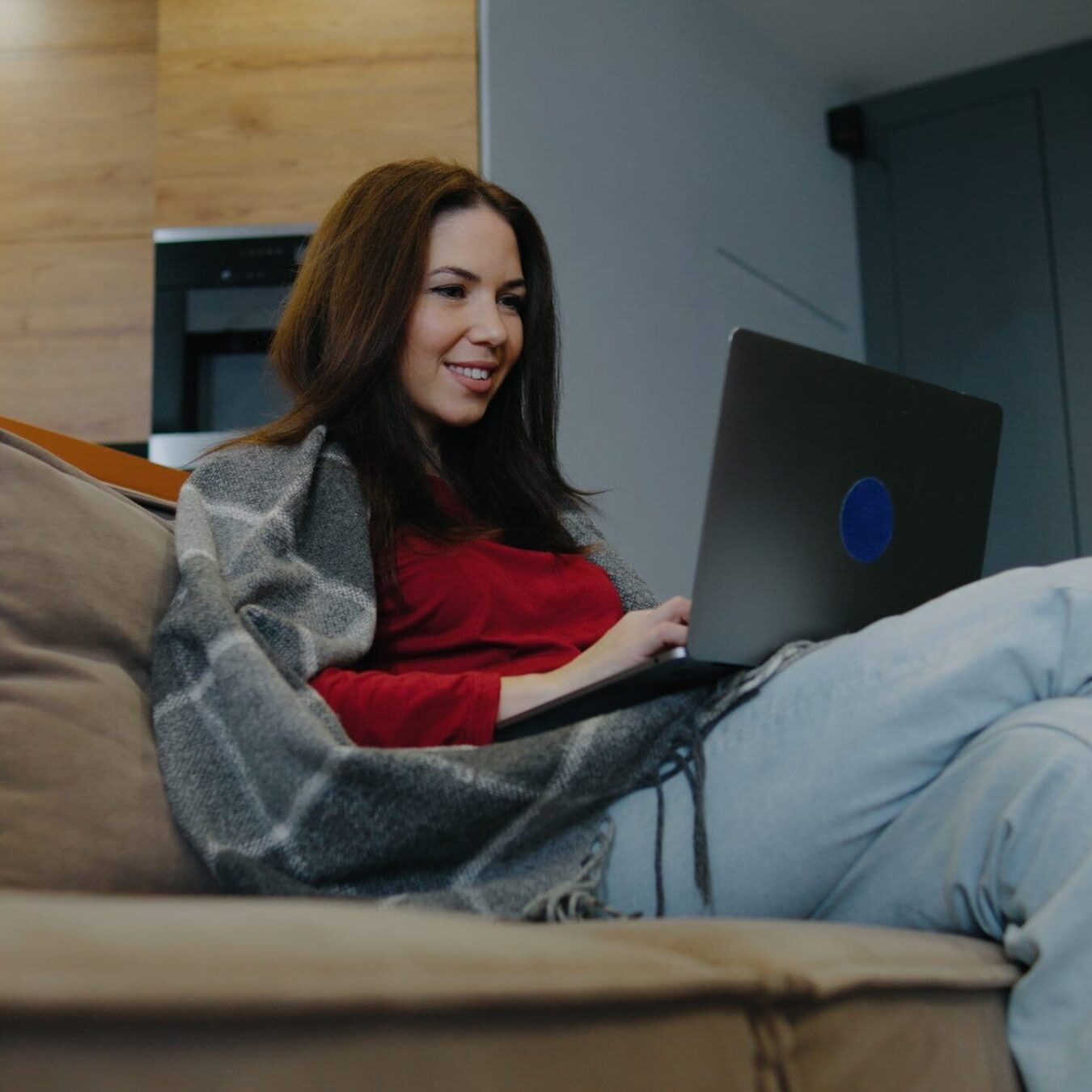 Woman sitting on a cozy sofa working on a laptop in a modern setting