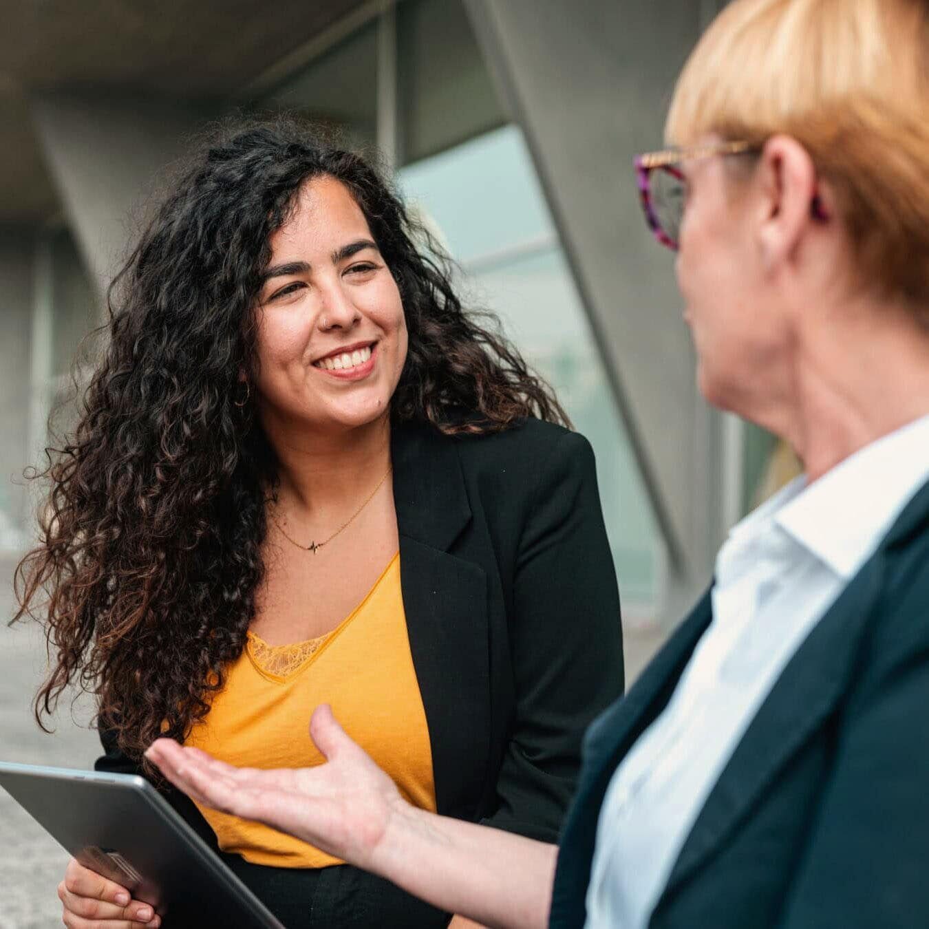 Two people compare the ICF Coaching credentials outside with an Ipad