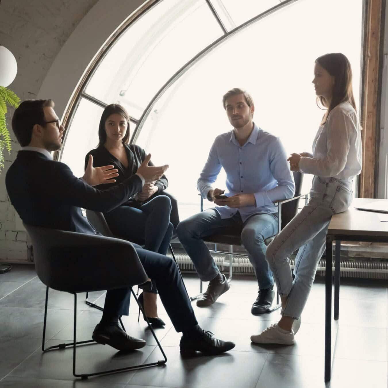 A group of people meet in a casual work environment to discuss coaching ethics.