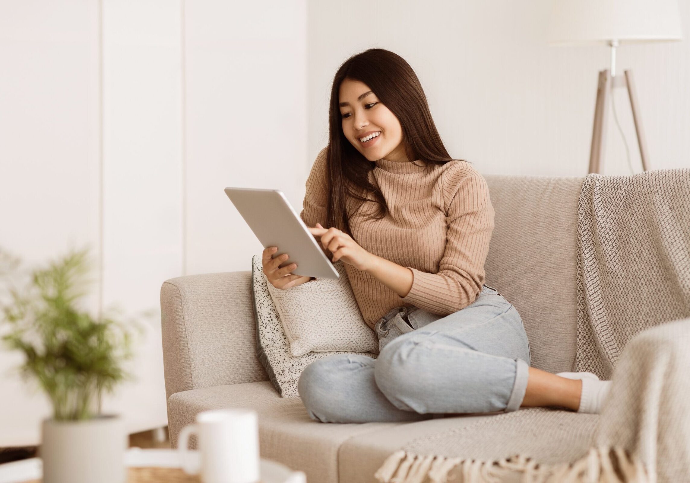 Woman sitting on couch at home using a tablet device