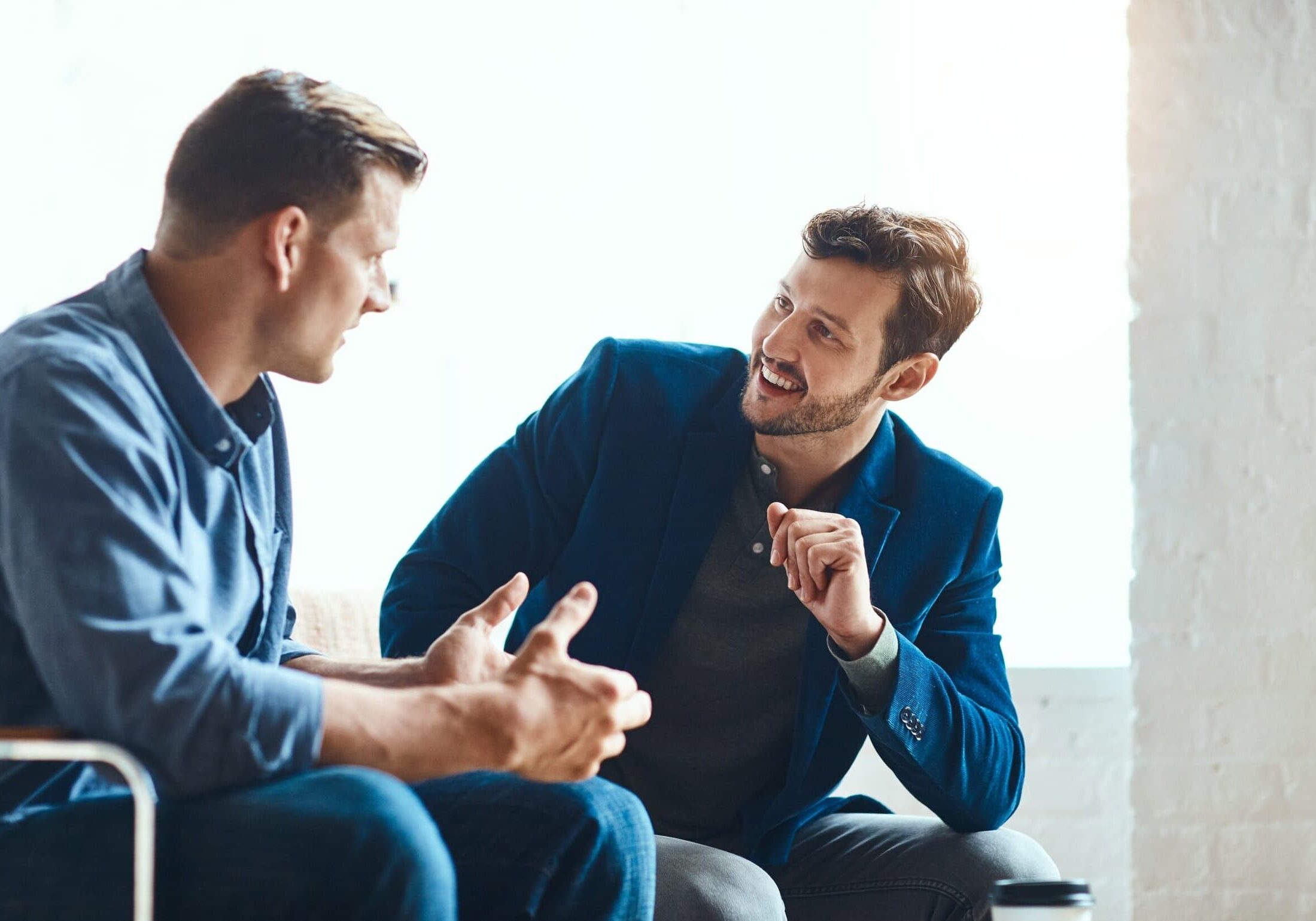 Two businessmen sitting and talking during a one-on-one coaching conversation