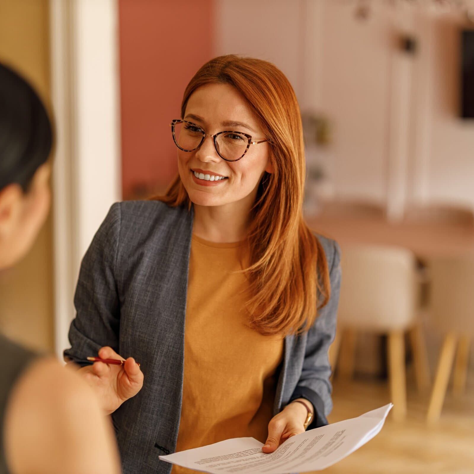 Professional woman holding document while speaking to colleague in office