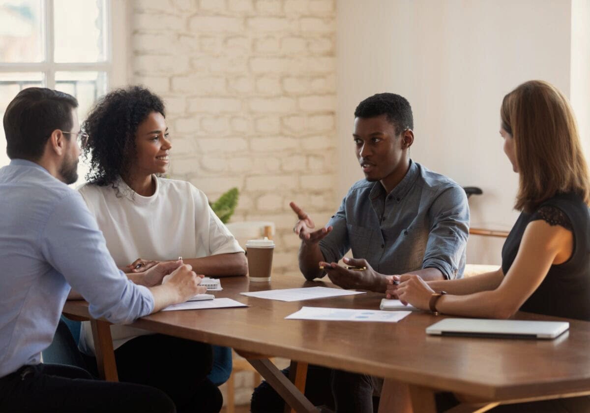 Four colleagues in a coaching session discussing ideas around a table.