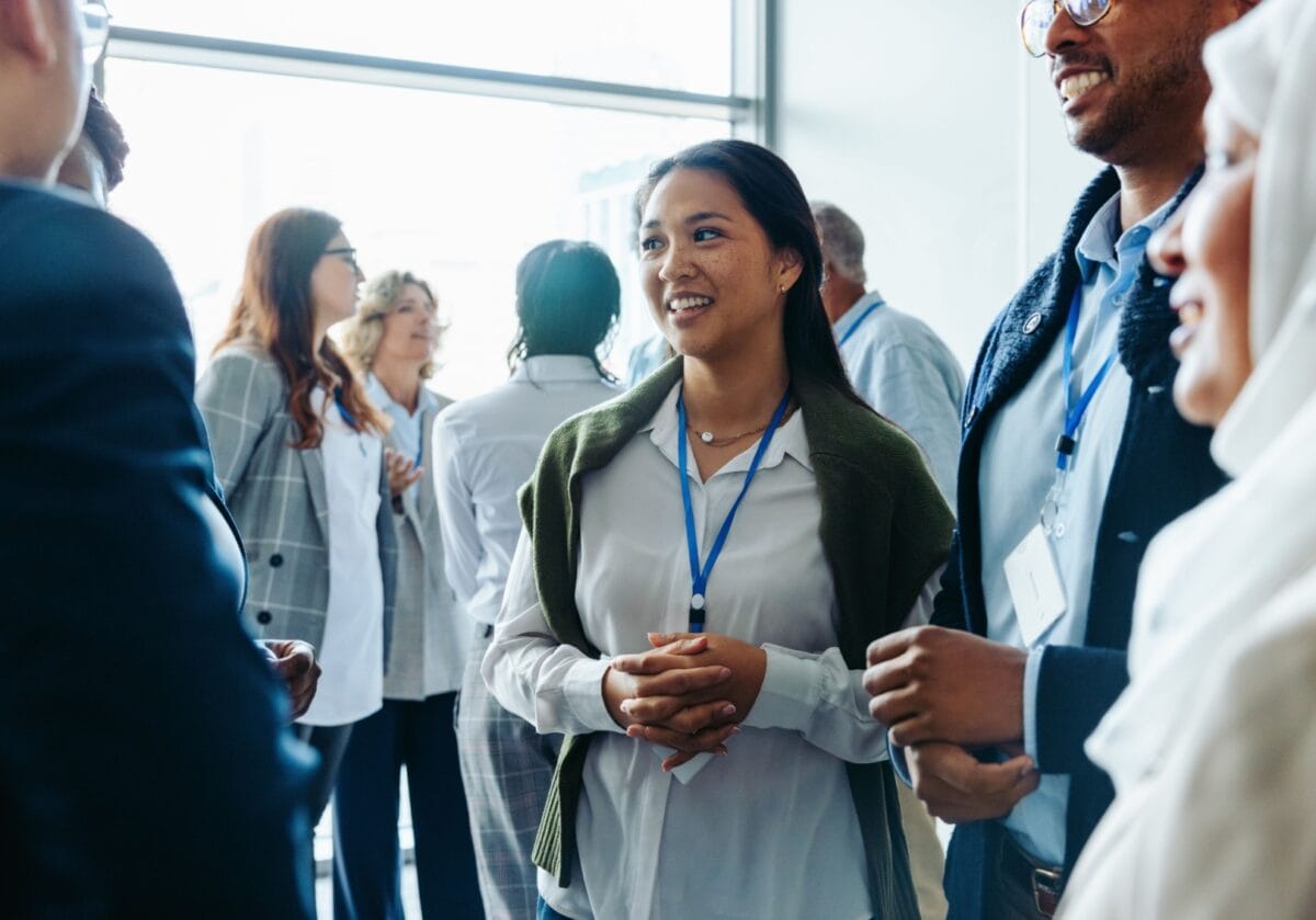 Young woman and diverse group of professionals networking at a daytime coaching conference.