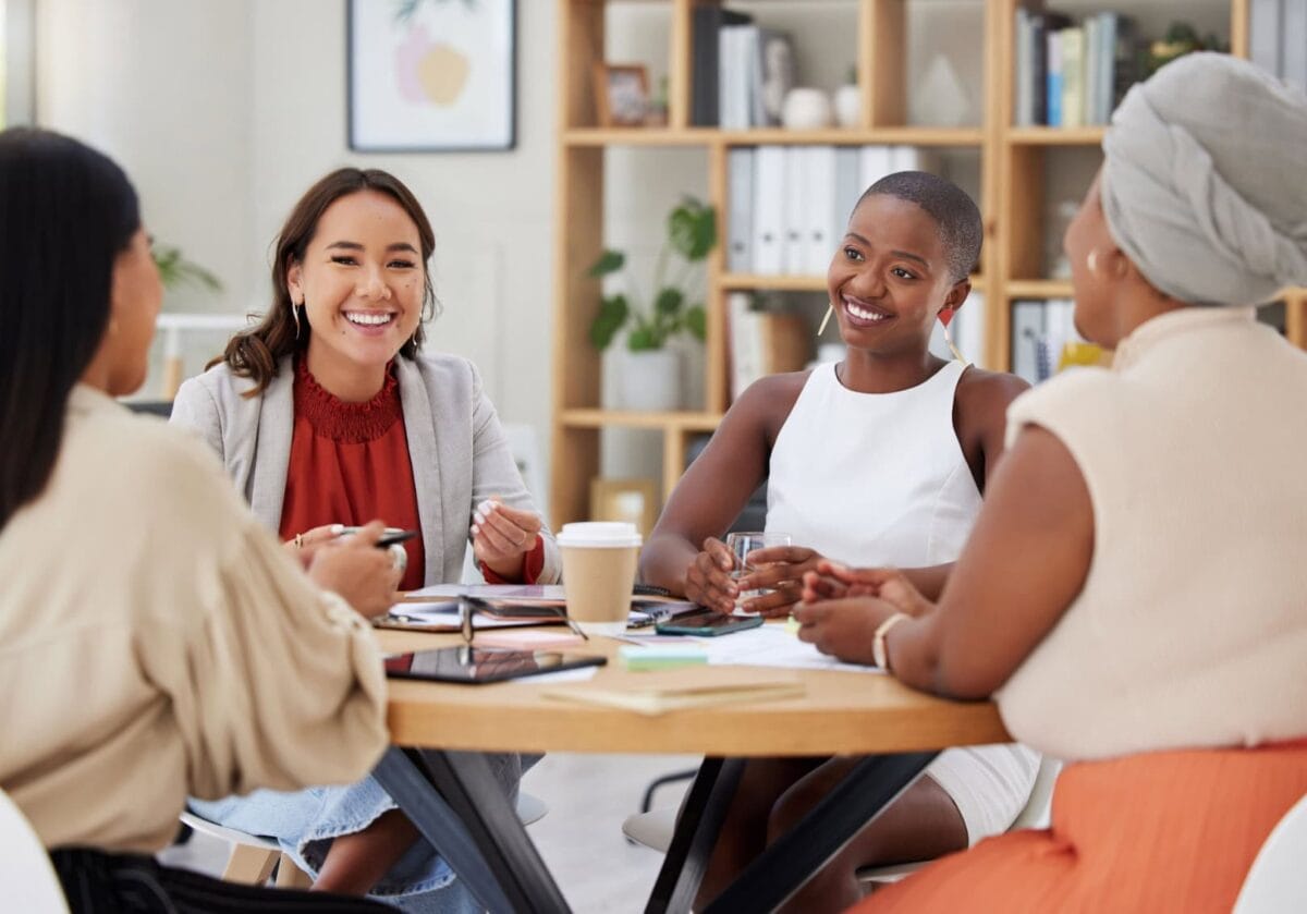 Four professionals smiling and collaborating at a business meeting.