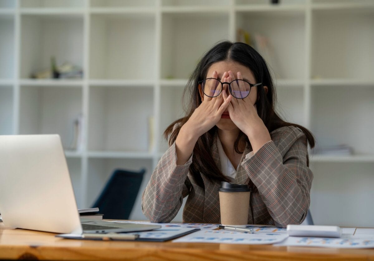 Stressed businesswoman rubbing her eyes at office desk