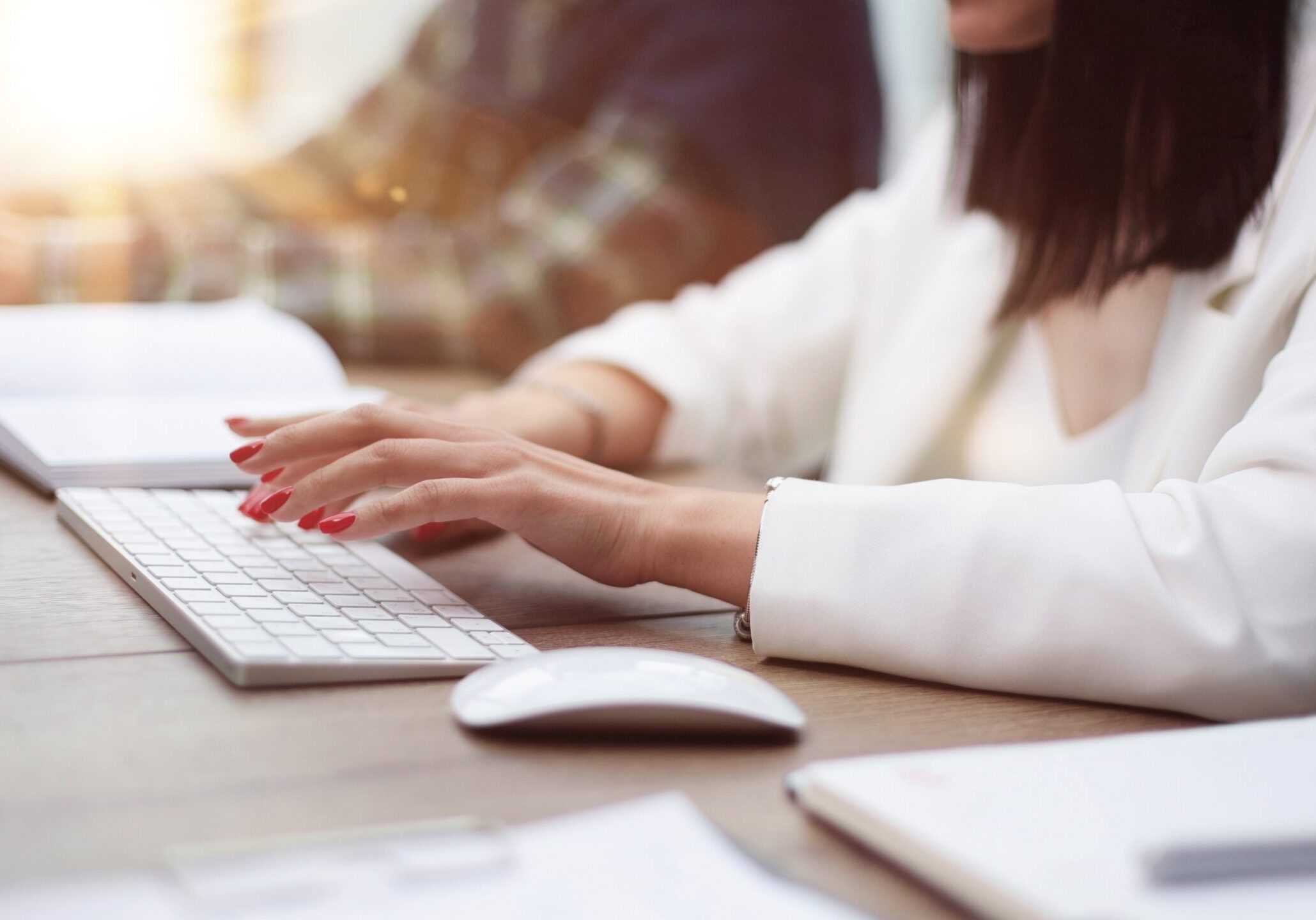 Professional typing on a keyboard while working at a desk with laptop and notebook