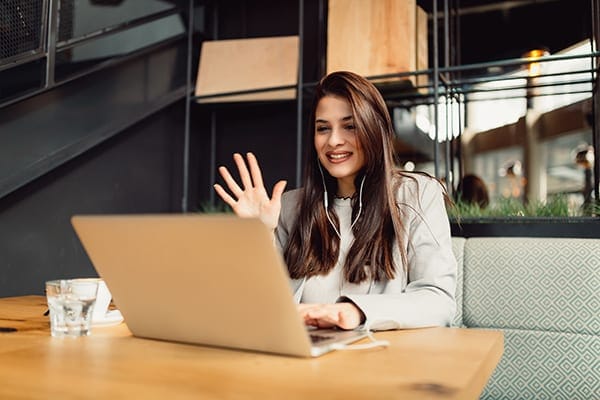 female coach meeting virtually with a client while sitting at a restaurant table