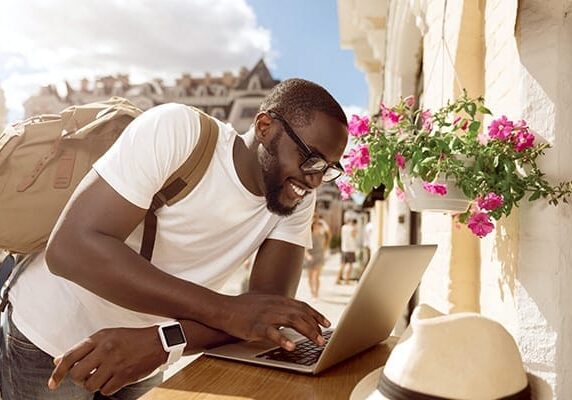 man in a Mediterranean setting working on a laptop as a digital nomad