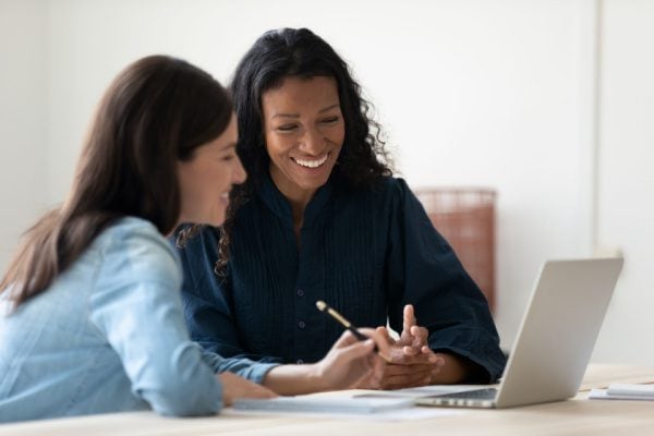 two women looking at a computer smiling on a video call with a coach
