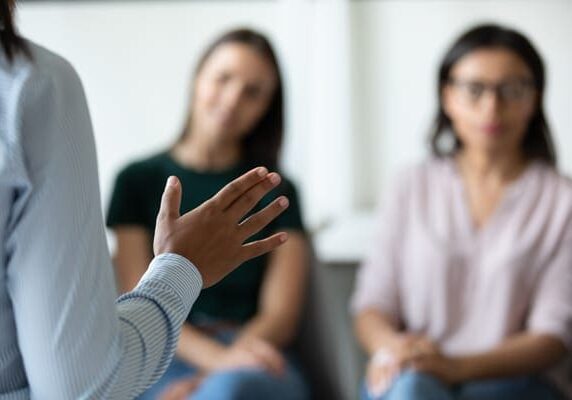 leader speaking to two seated women