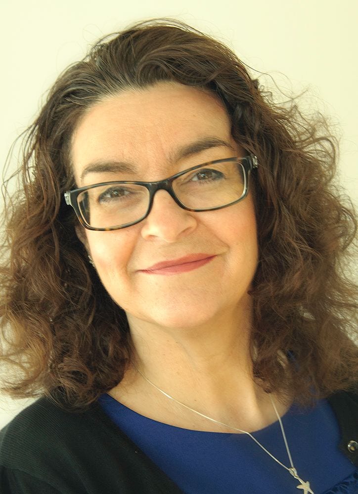 Michelle Lucas headshot photo, smiling woman with brown hair wearing a black sweater over a dark blue top in front of white background