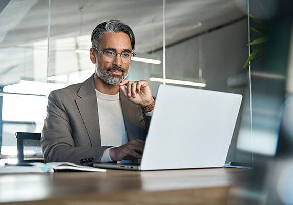 coach using a laptop at a table in an office