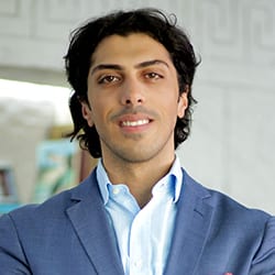 Mohammad Abdullah ACC headshot photo, dark haired man in a light blue suit smiling