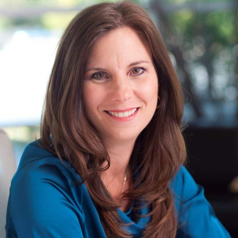Nancy Duarte headshot photo, smiling woman with brown hair wearing a blue top sitting outside