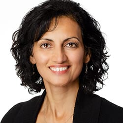 Neena Newberry MCC headshot photo, smiling woman with dark hair wearing a black blazer in front of a white background