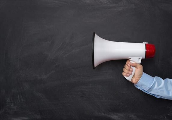 loudspeaker being held in front of a chalkboard