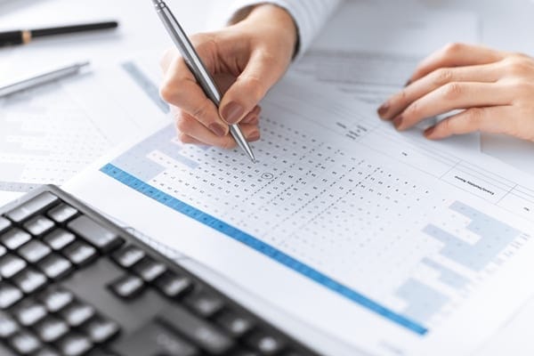 woman analyzing data on a piece of paper in front of a keyboard