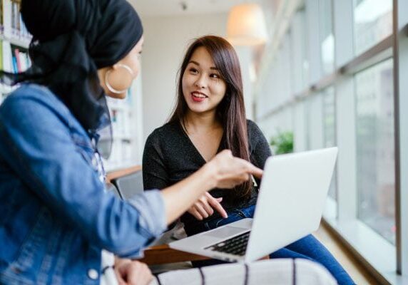 two people meeting and smiling in front of a laptop one client one coach