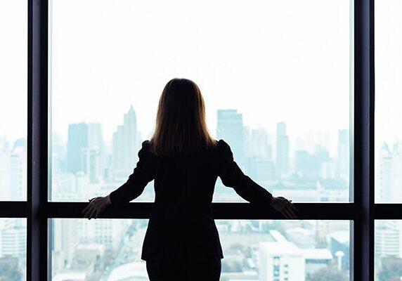 coach standing at a window looking over a city
