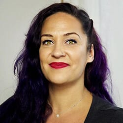 Shannon Whaley PCC headshot photo, smiling woman with dark hair wearing a dark top in front of a white wall