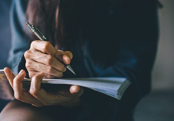woman holding papers and readying to write on them with a pen