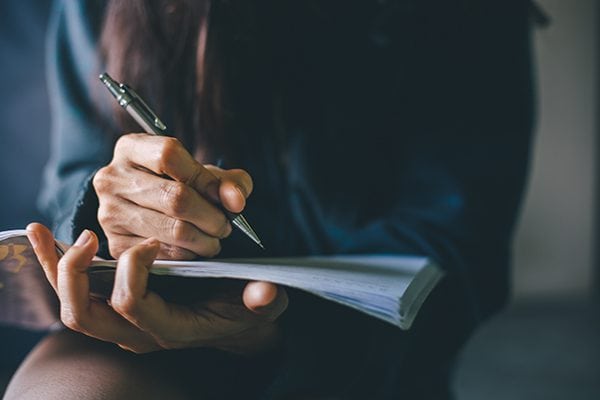woman holding papers and readying to write on them with a pen