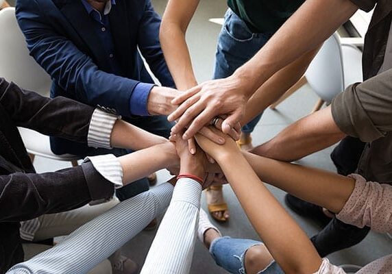 many people with hands in a circle working together