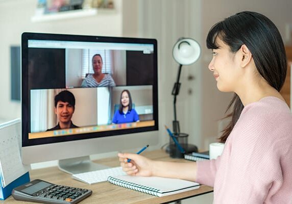 woman taking notes during an online coaching training session