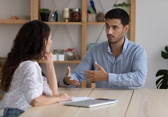 coach and client meeting at a table and the coach is speaking to explain something