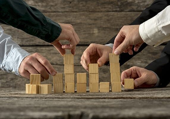 five people stacking cubed blocks of wood in different stacks