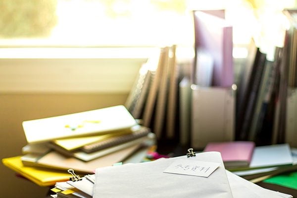 disorganized desk with piles of papers and files